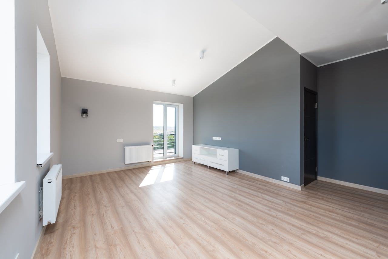 service-02 Wide-angle shot of a modern unfurnished apartment with wooden flooring and large windows.
